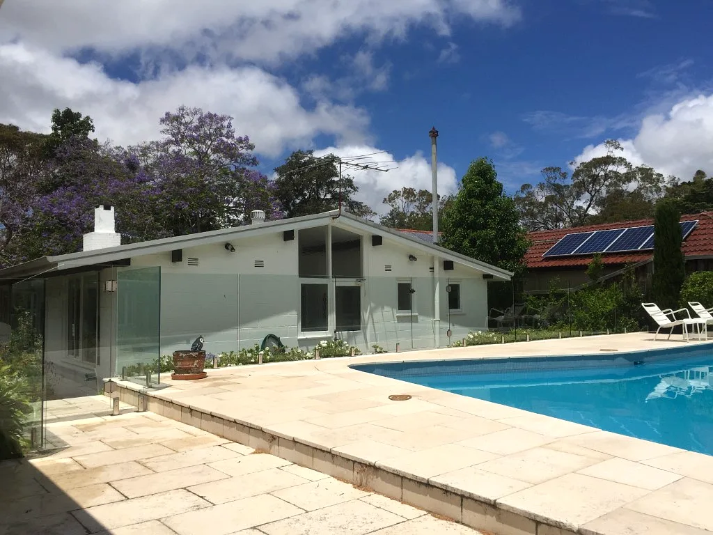 Glass pool fencing beside a house and outdoor pool area
