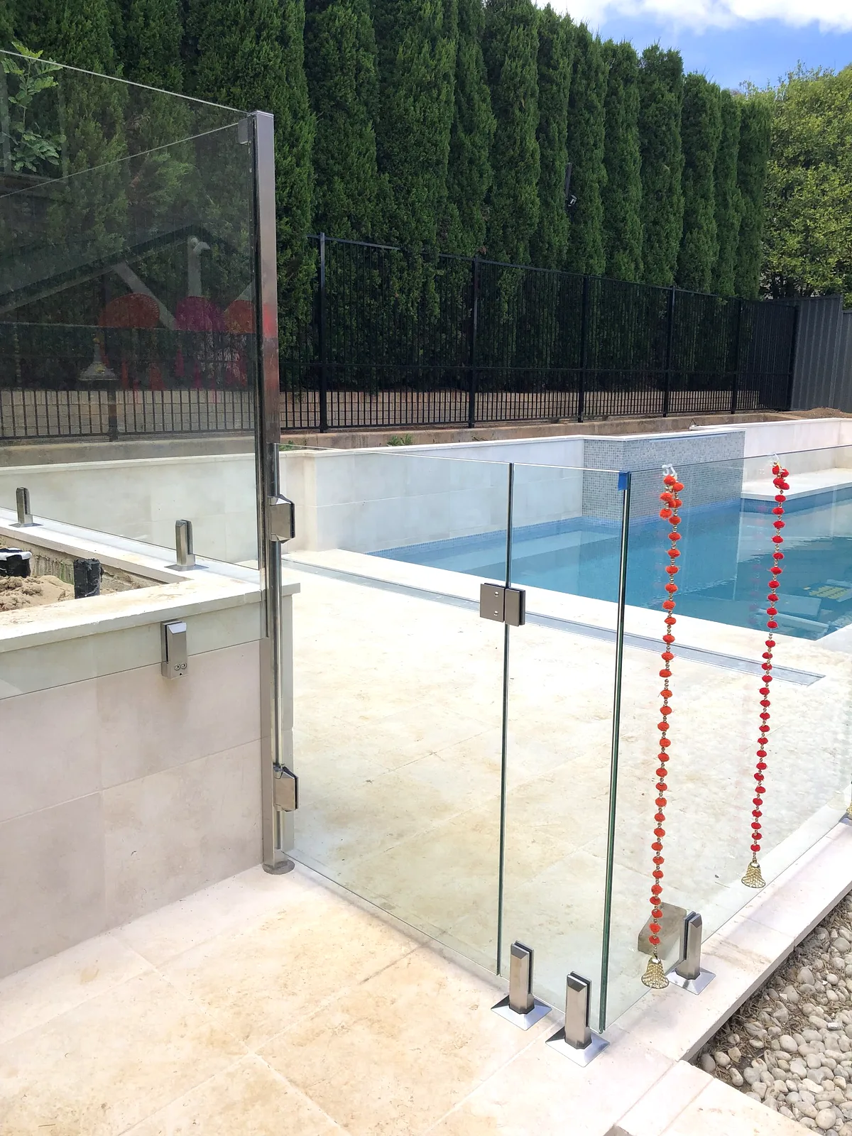 Glass pool gate within a frameless pool barrier